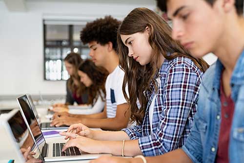 Students in a classroom setting working on laptops.