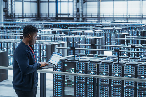 Man reviews readout beside racks and rack of electronics.